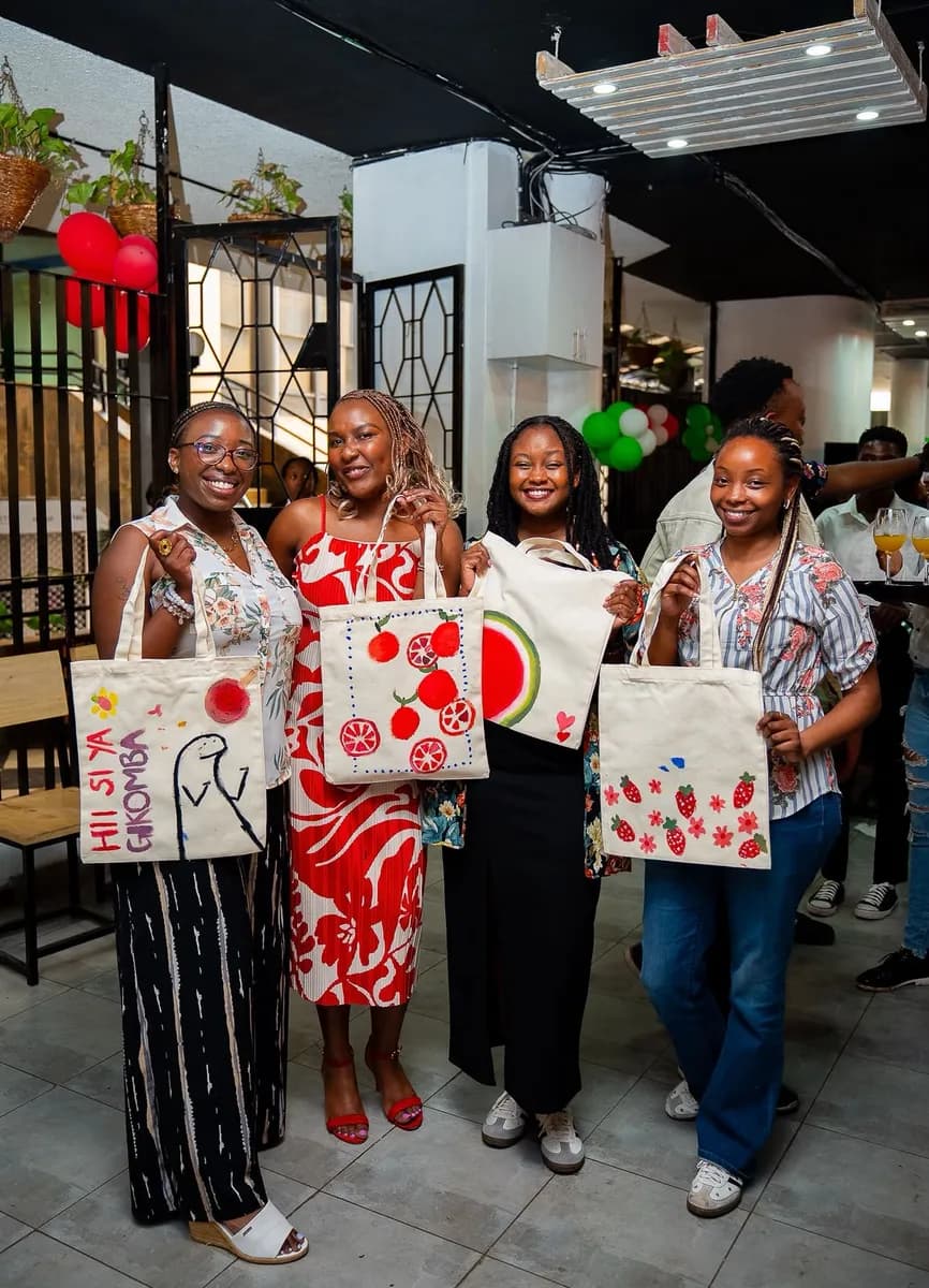 Participants showing the tote bags they painted at a SoulSisters corporate experience